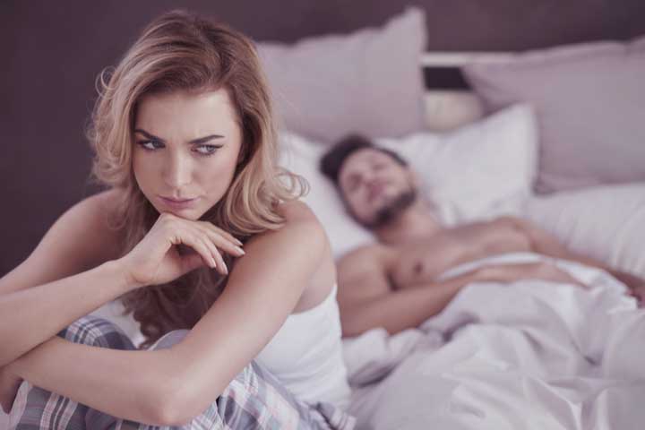 A woman in s sexless marriage sitting at bed disappointed from her husband