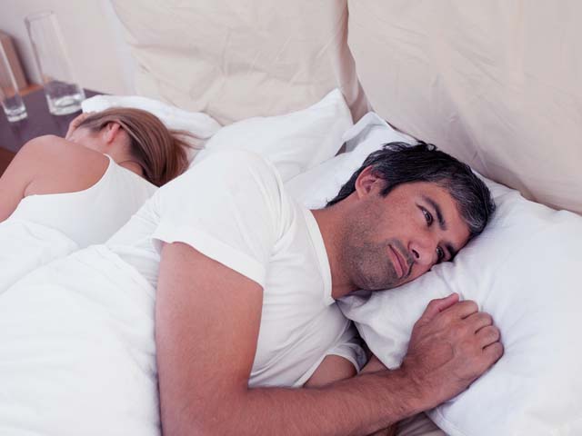 man lying in bed thinking about sexual performance anxiety erectile dysfunction