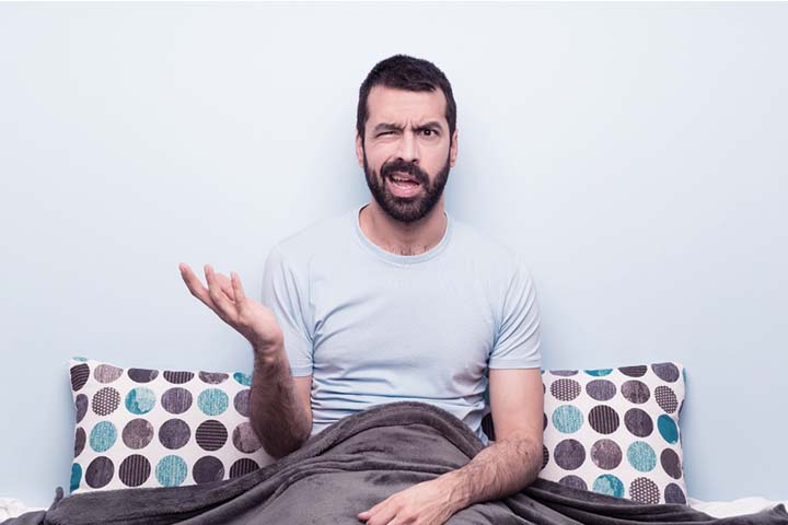 Man sitting in bed confused as to how can he have both high libido and erectile dysfunction